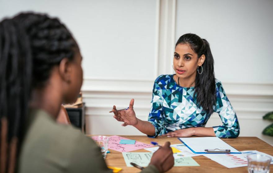 Two women of color discussing finances across a table