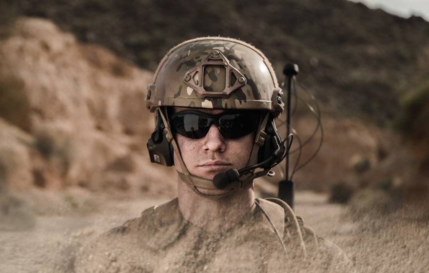 A man with sunglasses in military gear, in a desert
