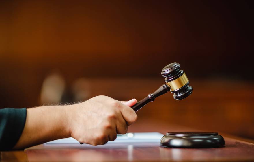 Closeup hand of a woman Judge with gavel at wooden table indoors at the courtroom