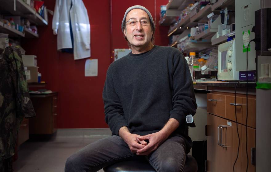 Kenneth S. Kosik seated in the lab, smiling in casual dress