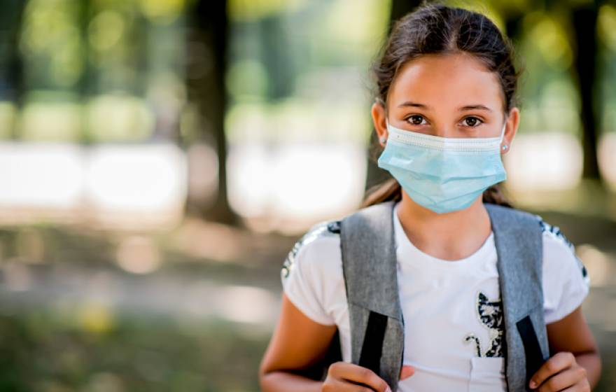 A child wearing a backpack and a mask