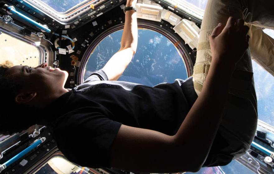 Jessica Watkins floats in the cupola of the International Space Station wearing a blue shirt and khakis