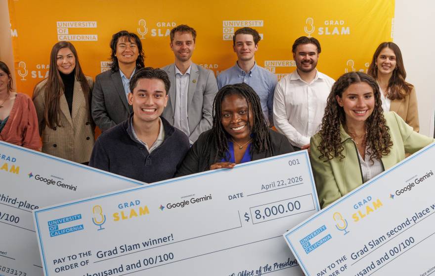 A group of smiling students, three of them holding giant prize money checks