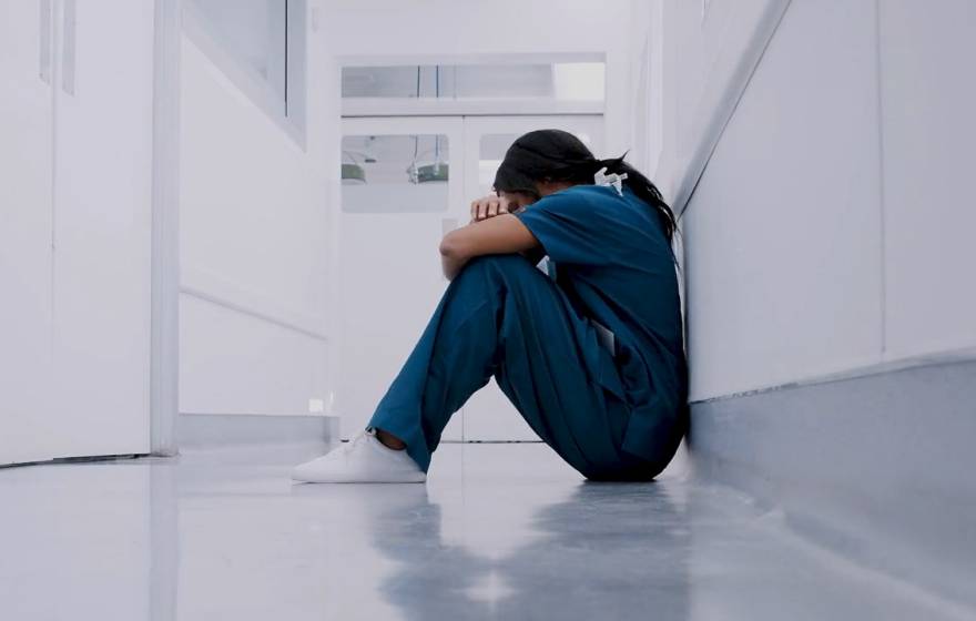 Health care worker sitting on ground frustrated