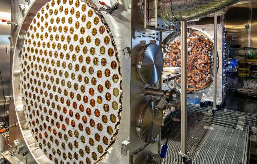 The LUX-ZEPLIN dark matter detector’s instrumentation, including a circular array of gold-toned sensors and wiring inside a clean room.