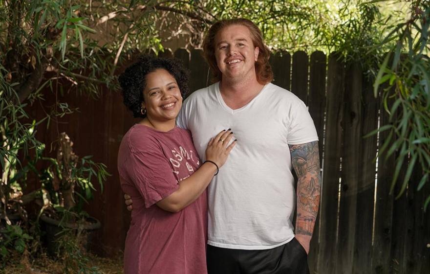 A woman with her hand on the chest of her male partner, who has long red hair