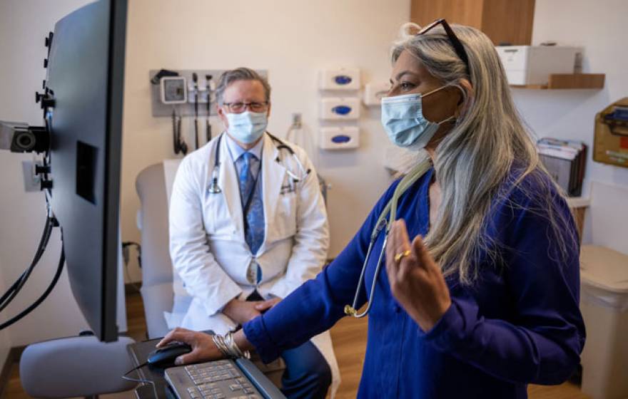 Two medical professionals in an office, one looking at a screen