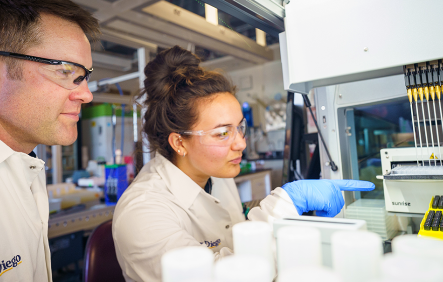 A man and a woman pointing at a machine in a lab