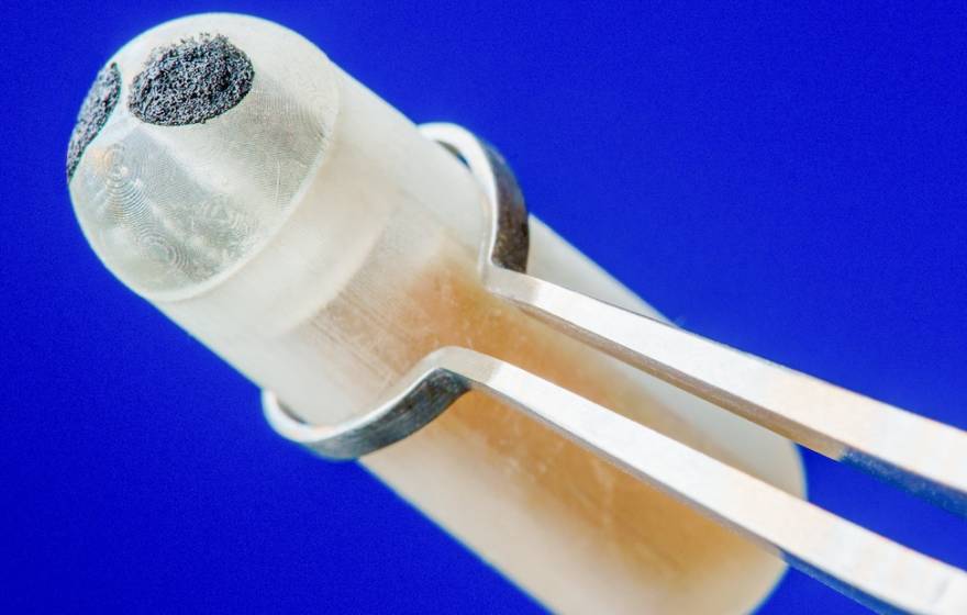 Ingestible sensor held by tweezers, close up