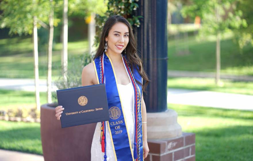 Monica Mary Xu English with her diploma, cap and gown