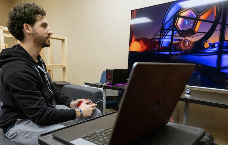 A young man with a beard playing a video game