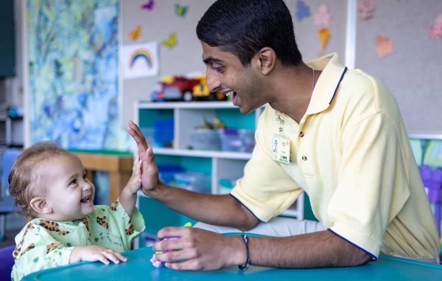 Neeraj Senthil high-fives a laughing baby at the children's hospital