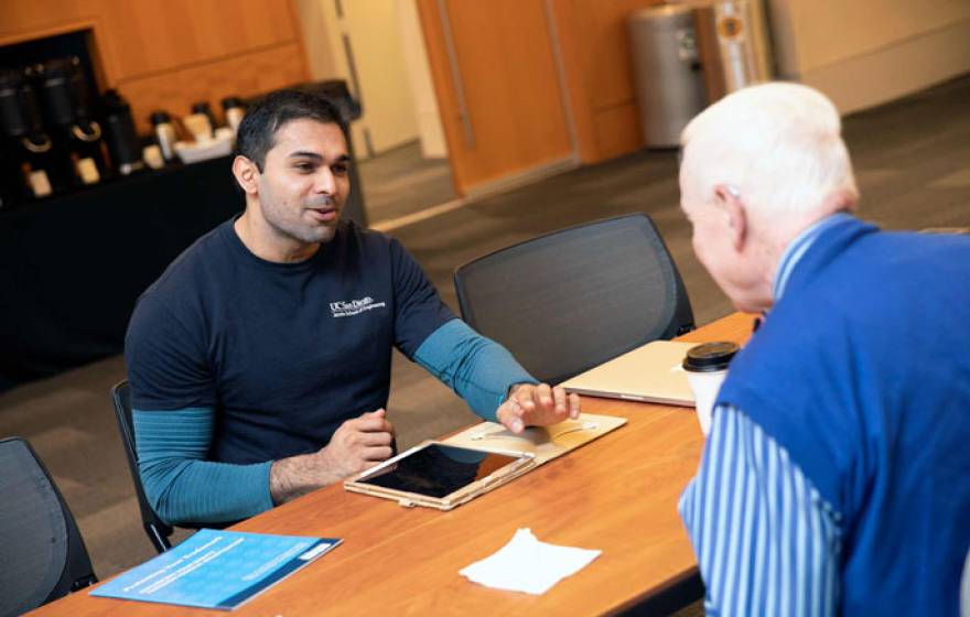 Gopesh Tilvawala speaks to someone across a table