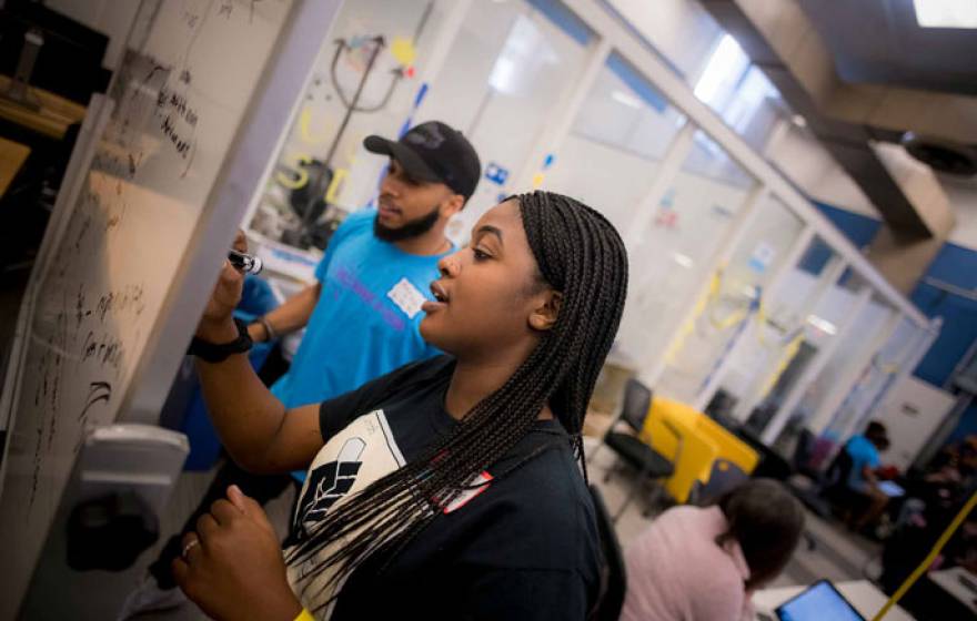 Two students work together on a whiteboard