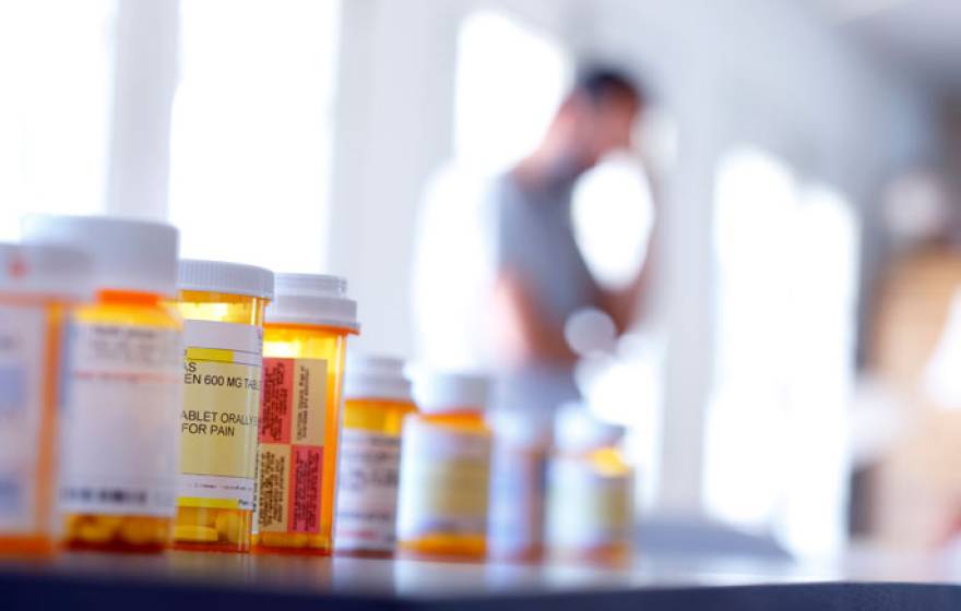 Opioid bottles with a man in the background