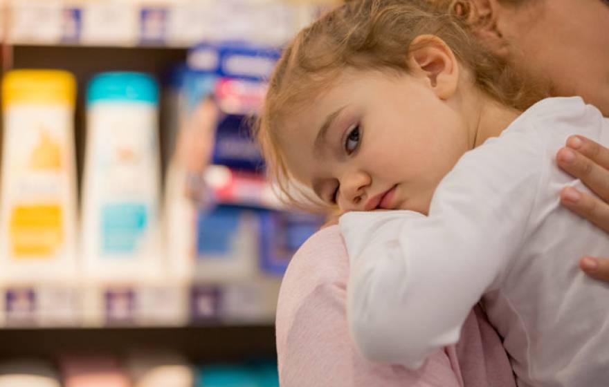 Child on parent's shoulder in front of personal care products