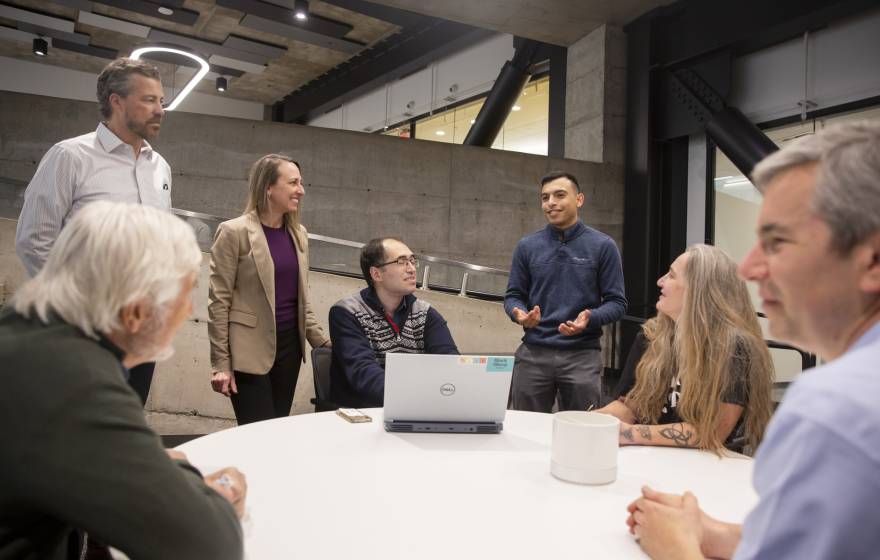 A group of people discussing, a few standing, while in an industrial or modern office space