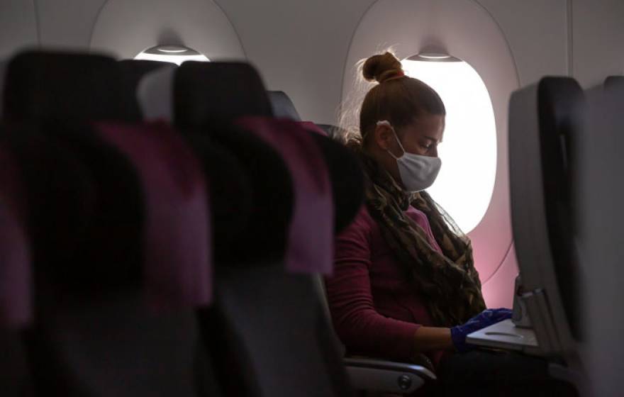 Woman on a plane wearing a mask alone in her row