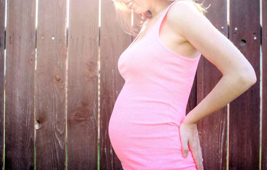 Pregnant woman in front of a fence