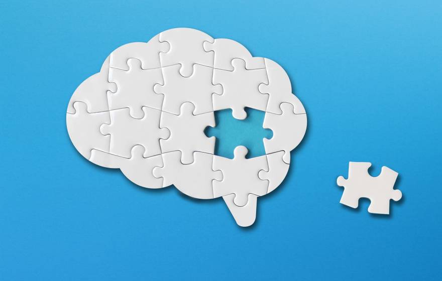 A puzzle of a brain with one piece to the side; puzzle is white on a blue background