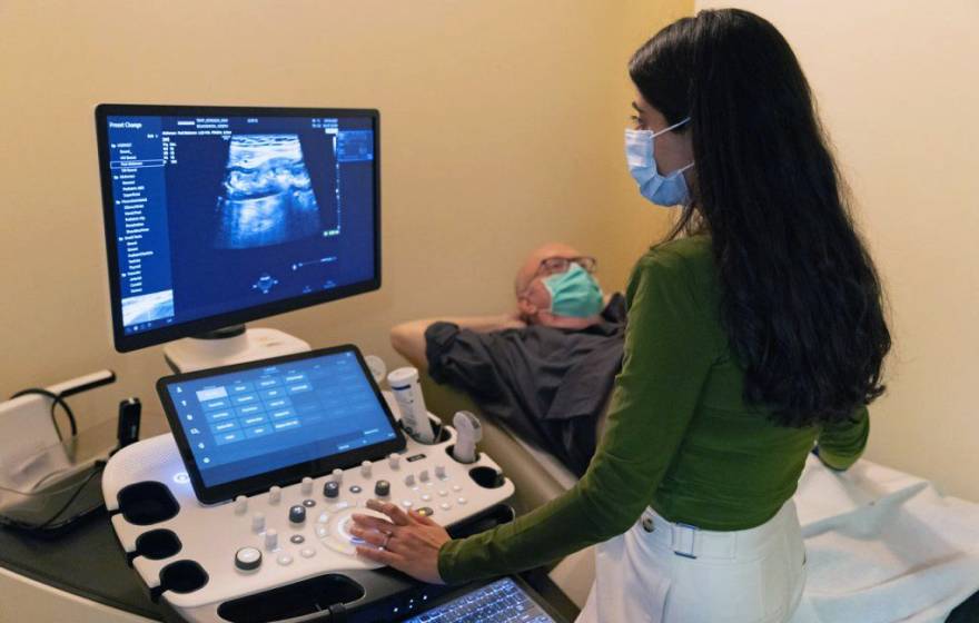 A doctor looking at a patient's ultrasound while the patient reclines nearby