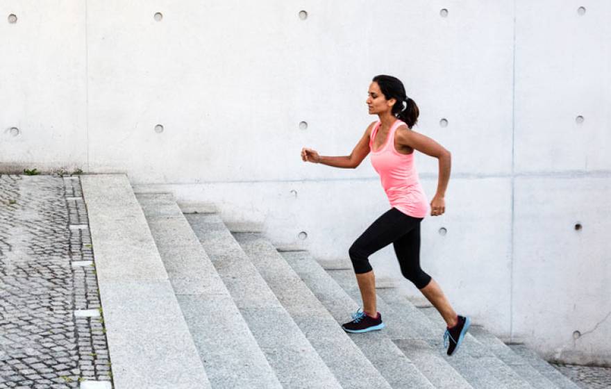 Woman jogging up grey steps outdoors
