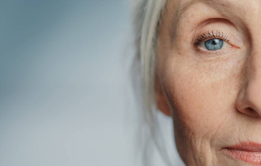 Senior woman with gray hair and blue eyes looking ahead straight at the camera