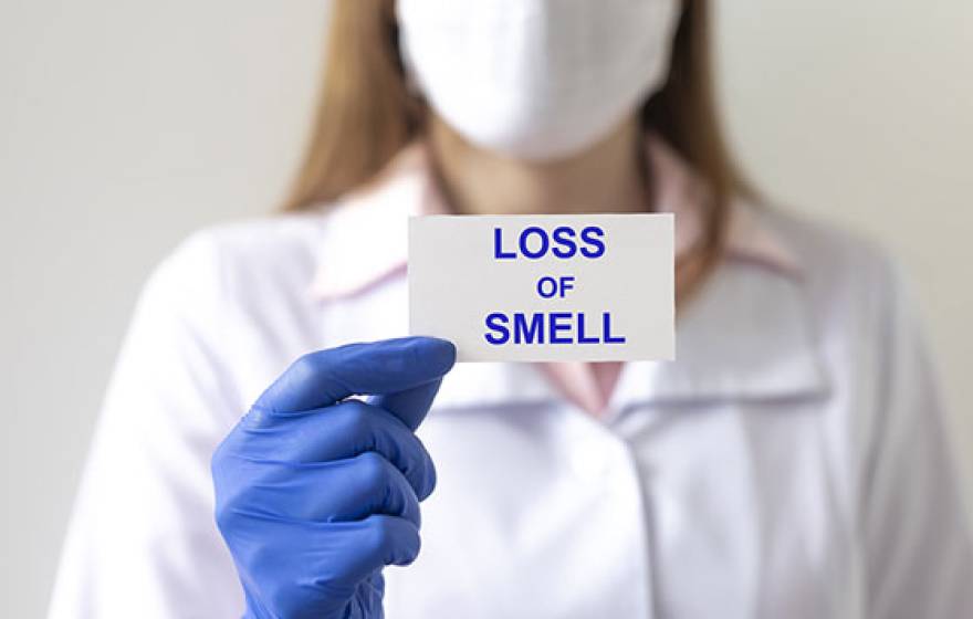 Nurse holds card saying 'loss of smell'