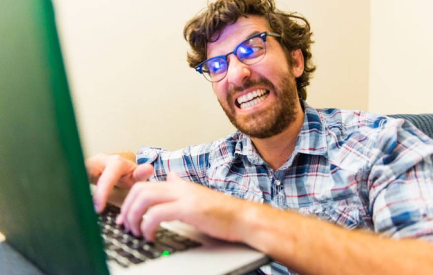 Outraged man typing on computer