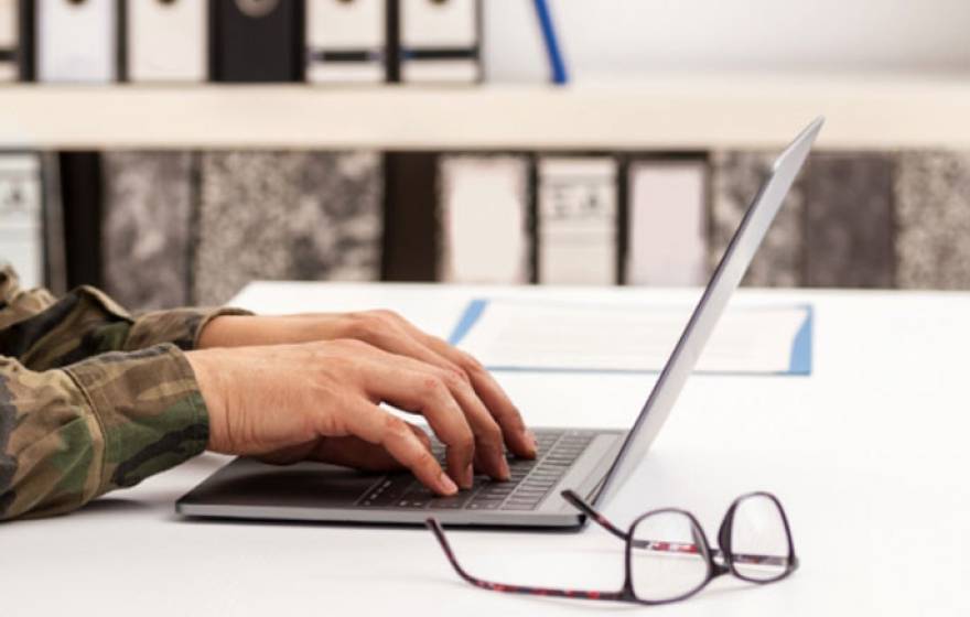 Soldier typing on a laptop