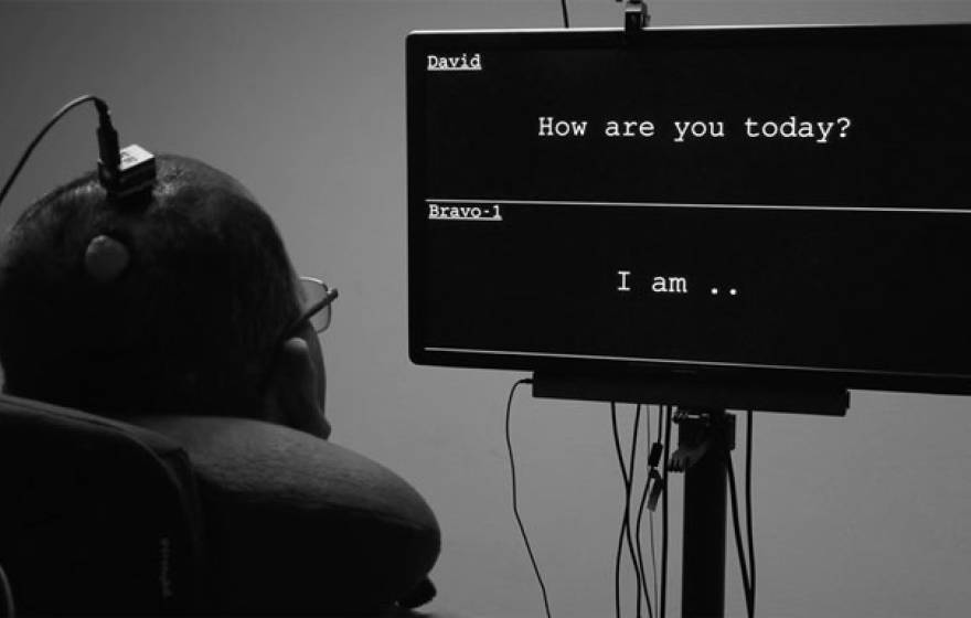 A man looks at a screen where his words appear while wearing a device on his head