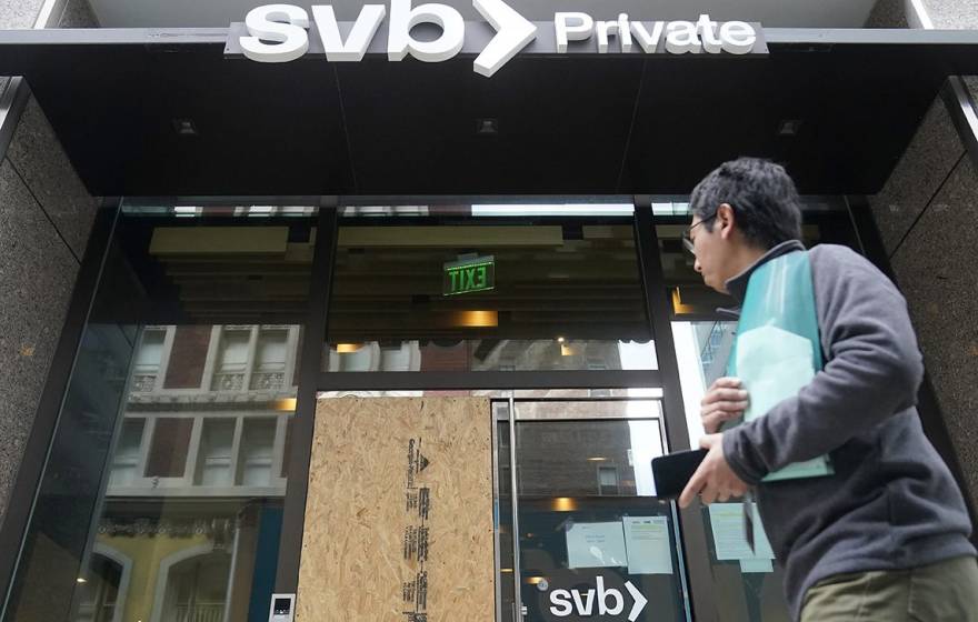 Someone walks by the SVB bank with one door boarded up