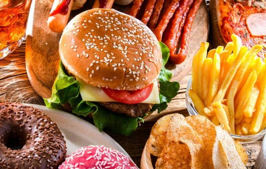 A photo of a table with chips, beer, a burger, pizza, french fries, tacos and ribs