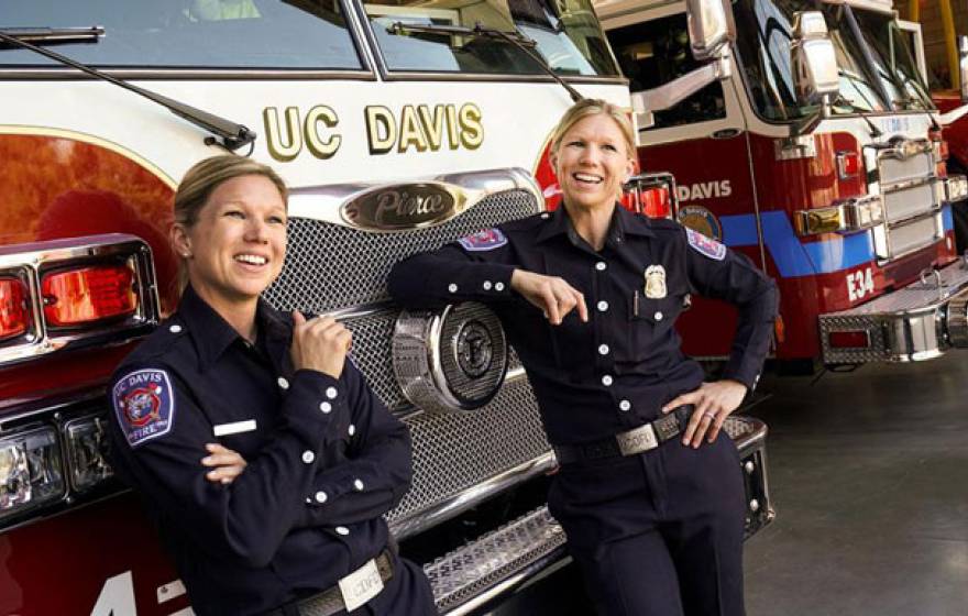 Twin firefighters pose in front of a fire truck
