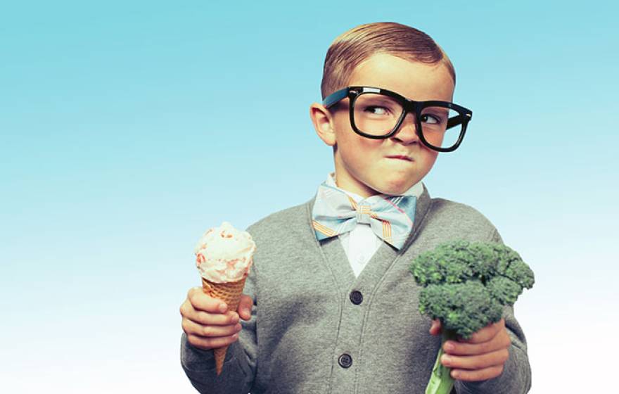 Mischievous boy holds ice cream and broccoli
