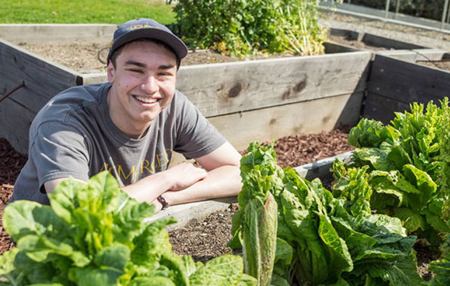 Young man smiles in campus garden