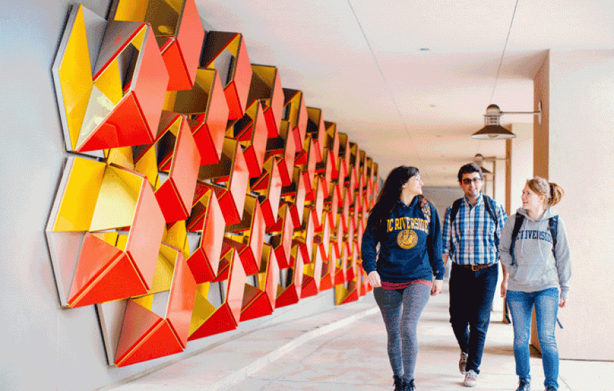 Three students walking a colorful UC Riverside hallway