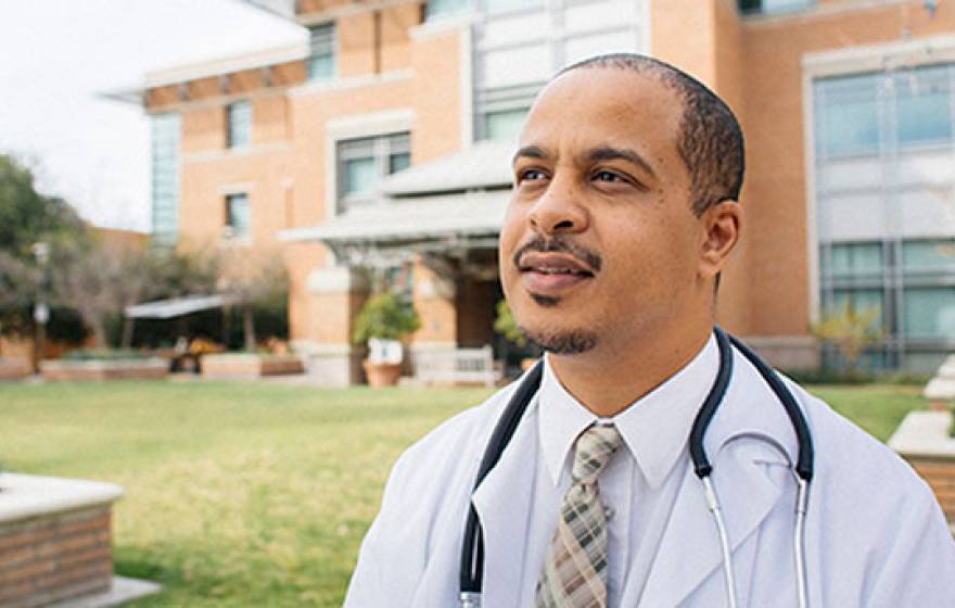 A Black professional stands in front of a brick office area