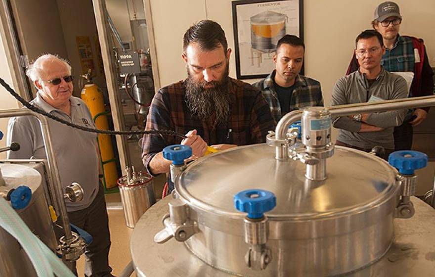 Professor Charlie Bamforth, left, and brewer Joe Williams, second from left, confer as beer is brewed in the UC Davis brewery.