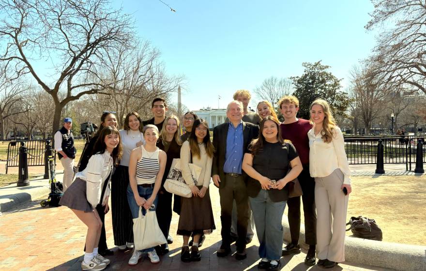 A group photo of people outside, Washington Monument and the White House behind