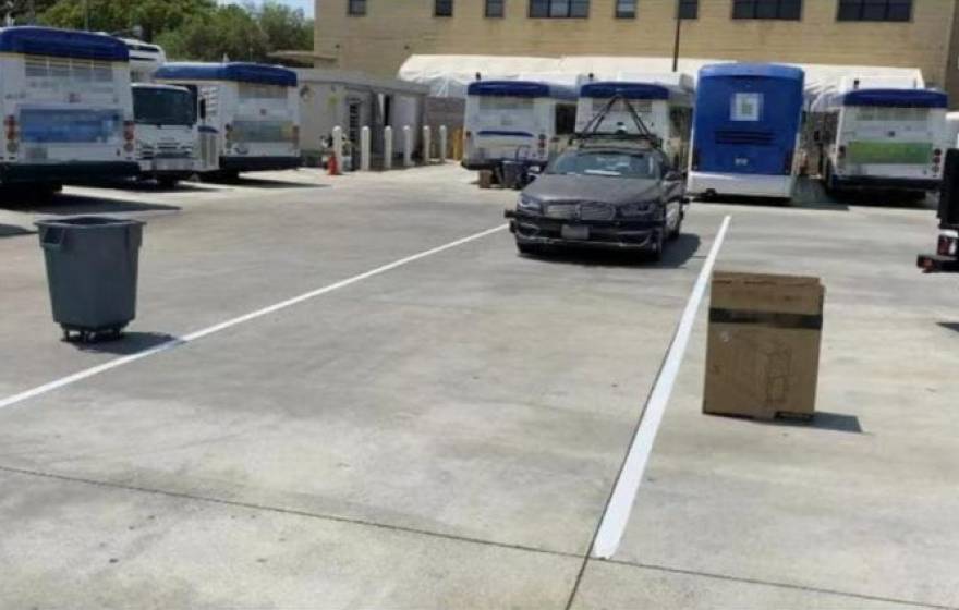 An autonomous car being tested by several common objects, including a trash bin