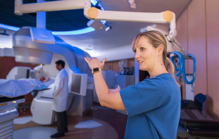 A nurse explaining something while a scan happens behind, doctor standing by