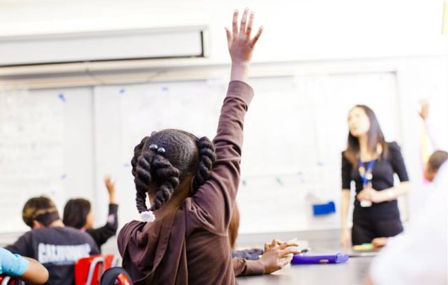 child raises hand in a classroom