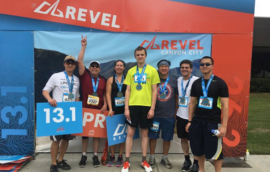 Tony Flores makes a victory sign as he stands at the finish of the half-marathon with his daughter, doctor and heart-failure researchers from UCLA, who ran to support Flores' efforts.