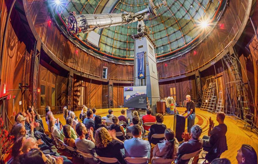 A presentation inside Lick Observatory, telescope visible, taken from a fish-angle lens