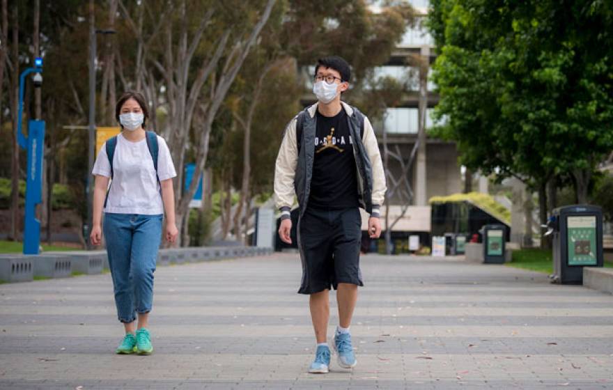 Two students walk with facemasks on