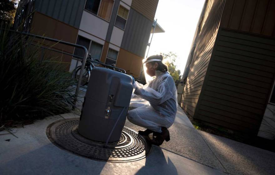 A woman in PPE tests wastewater on campus