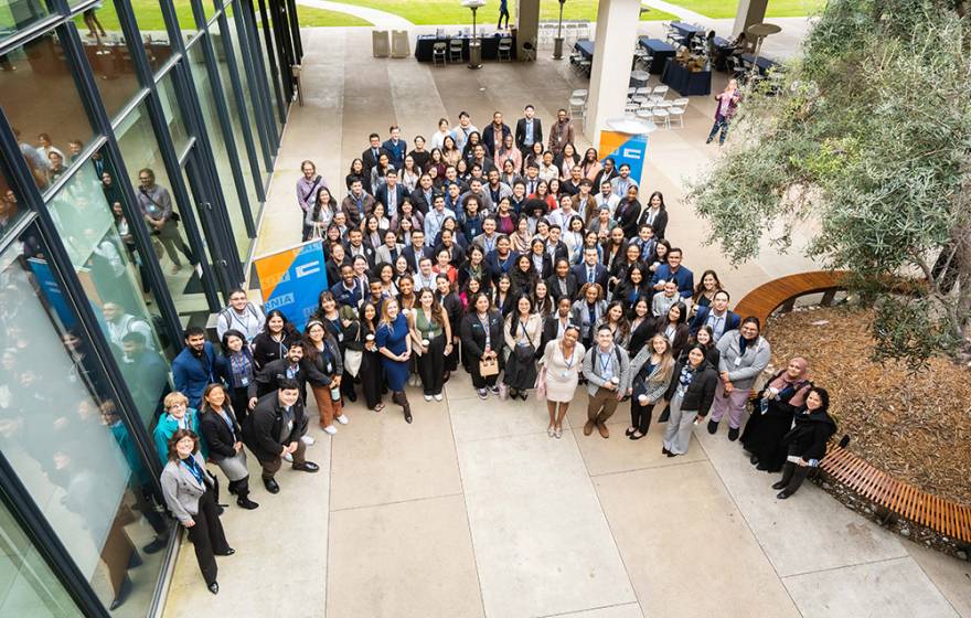 A group photo taken from above of ~200 young medical students in business attire, gathered in a courtyard.