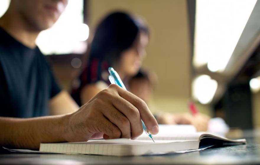 A generic student writing in a notepad face blurred