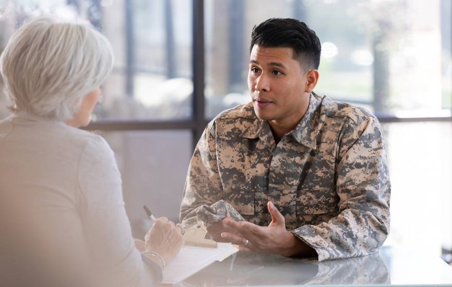 A soldier in uniform consults with a healthcare worker, discussing personal matters in a professional office